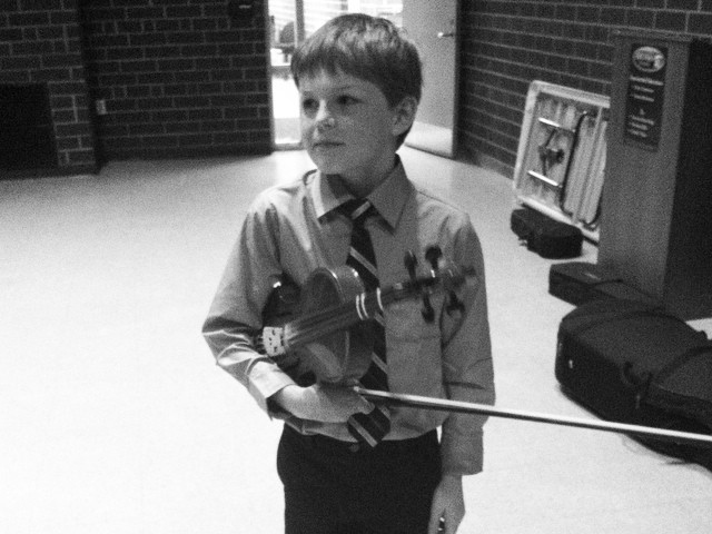 A Little Boy in a Tie Holding a Stick in Black and White