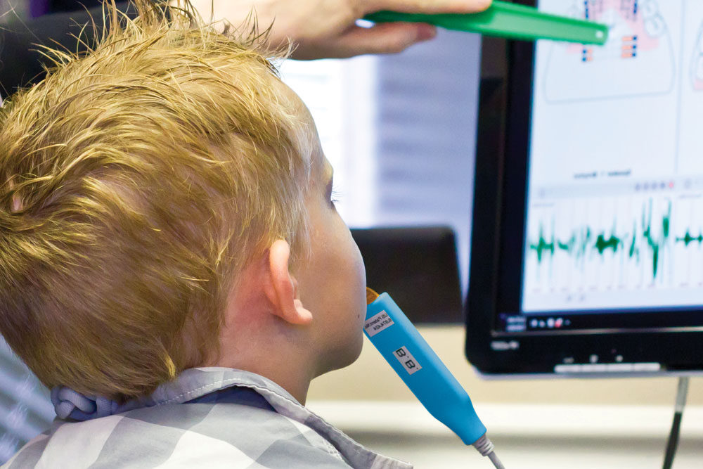 A Boy Looking at a Computer Screen Licking a Lollypop