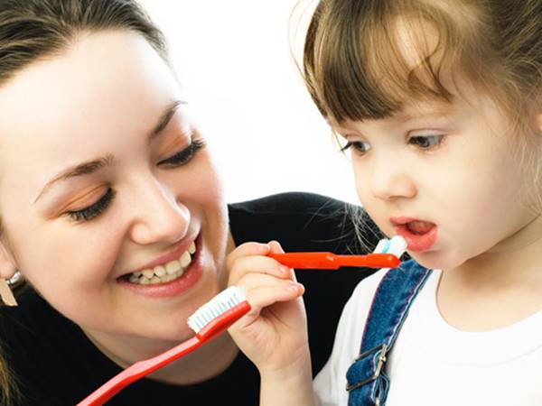 A Little Girl Holding a Red Color Toothbrush