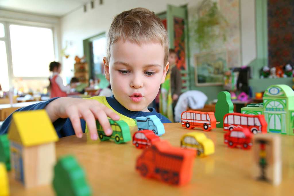 A Boy Playing With Toy Busses on a Table